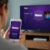 Person using a smartphone with the Roku app to turn on their Roku TV, demonstrating one of the methods to use the TV without a physical remote.